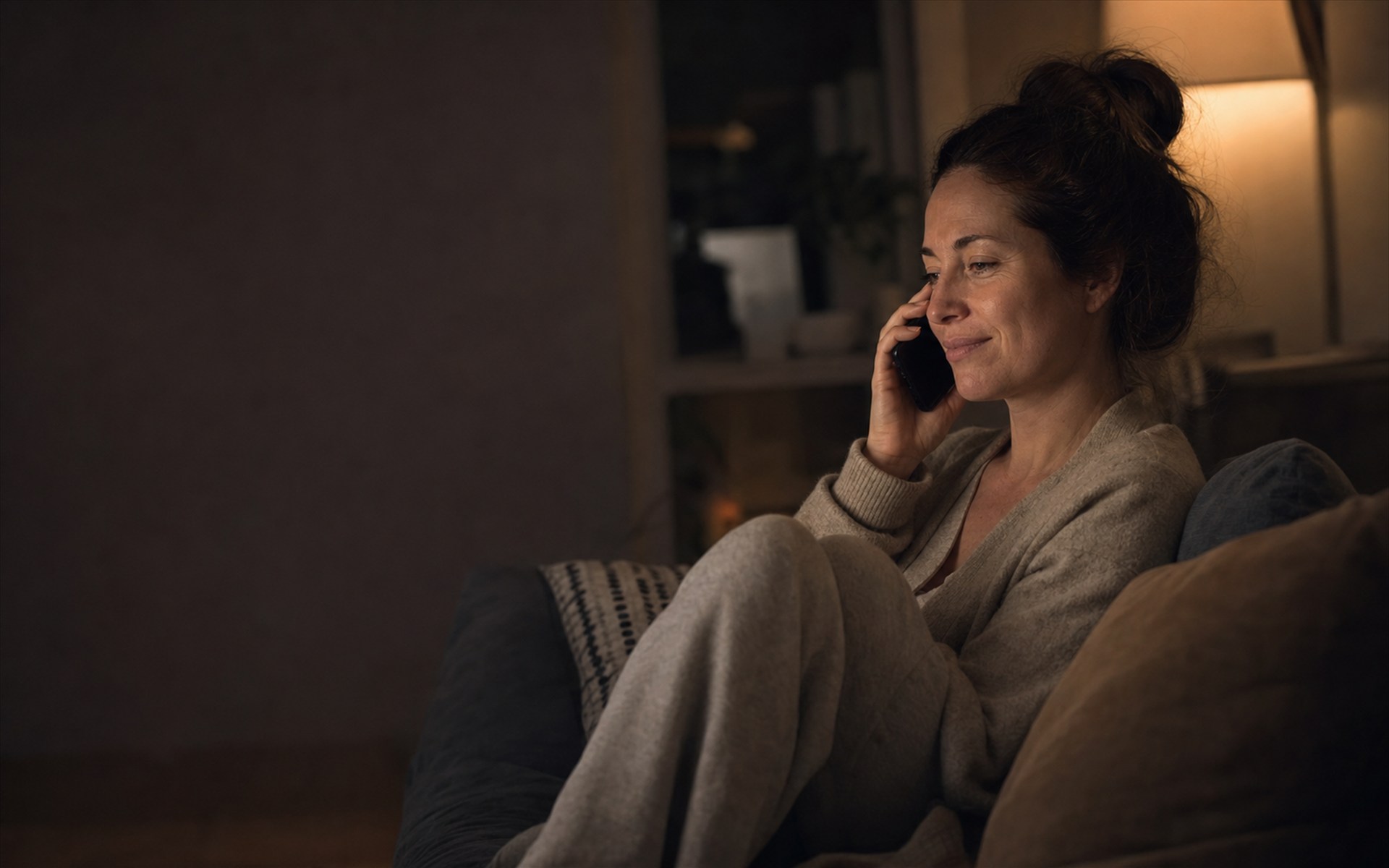 A woman relaxed on her sofa in the evening, talking to her doctor on the phone
